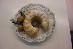 Bild von einem Gugelhupf auf einem weißen Teller mit blauem Muster, dekoriert mit Nüssen und Tannenzweig