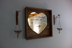 Bild von einem Wandspiegel in Herzform, auf dem der Spruch 'Wer Schmetterlinge lachen hört, weiß wie Wolken schmecken ...' aufgemalt ist