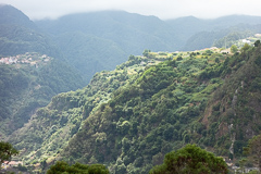 Wolken kommen über die Gipfel und die Sonne scheint noch auf einen Teil des Berghangs