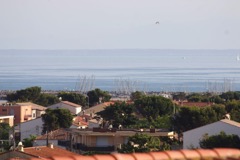 Blick von der Dachterrasse aus über St. Pierre und einen kleinen Yachthafen auf das Meer