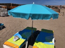 Zwei Liegen mit Auflagen, dazwischen ein Sonnenschirm. Was braucht man mehr am Strand? Cocktails! Auch die gibt es hier.